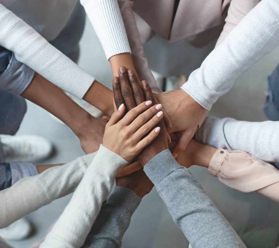 Close up of international business team showing unity with putting their hands together on top of each other. Concept of teamwork, top view